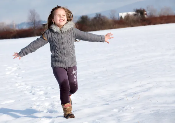 Ragazza che corre sulla neve nel parco — Foto Stock