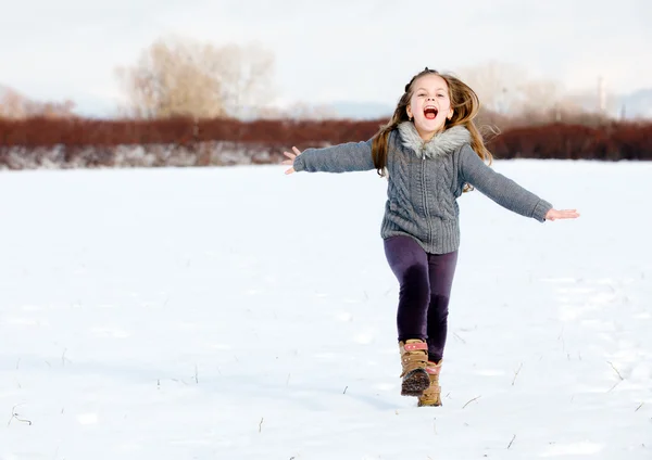 Flicka kör på snö i park — Stockfoto