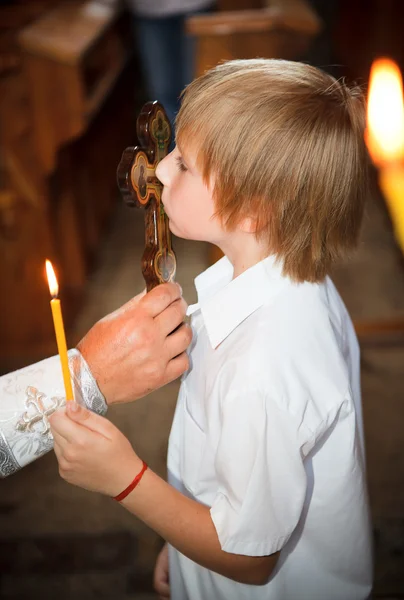 Маленький мальчик целующийся крест в церкви — стоковое фото