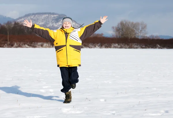 Ευτυχισμένο αγόρι που τρέχει στο χιόνι στο πάρκο — Φωτογραφία Αρχείου
