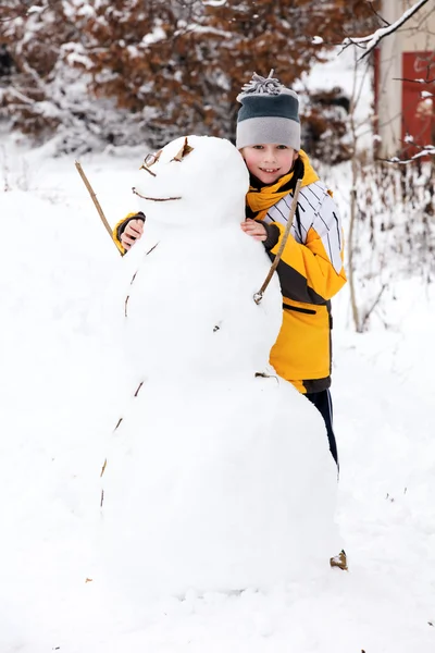 Ragazzo e un pupazzo di neve - una vacanza invernale — Foto Stock