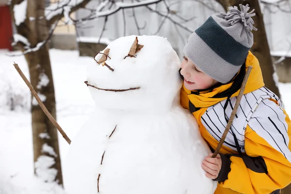 Menino e um boneco de neve - umas férias de inverno — Fotografia de Stock
