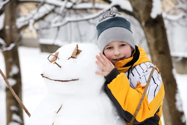 El muchacho y el monigote de nieve - las vacaciones invernales —  Fotos de Stock