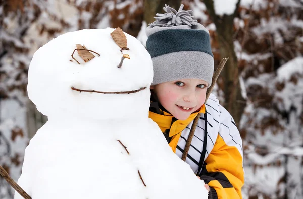 El muchacho y el monigote de nieve - las vacaciones invernales —  Fotos de Stock