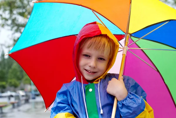 Мальчик с зонтиком стоит под дождем — стоковое фото