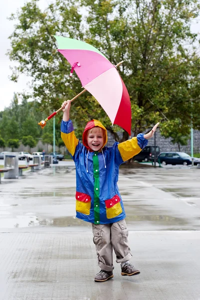 O rapaz com um guarda-chuva debaixo de uma chuva — Fotografia de Stock