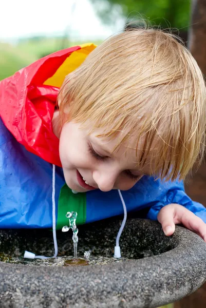 Le petit garçon qui boit de l'eau dans le parc — Photo