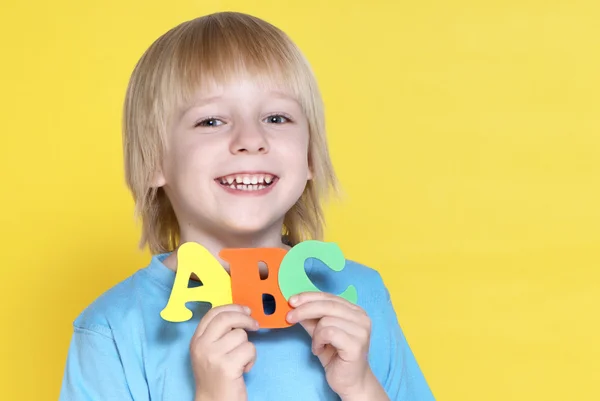 Маленький школяр з літерами на жовтому тлі — стокове фото