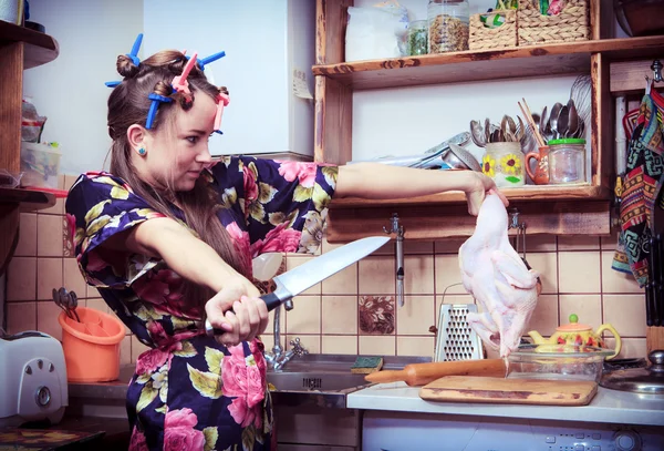 The silly housewife with knife and carcass of a hen in hands — Stock Photo, Image