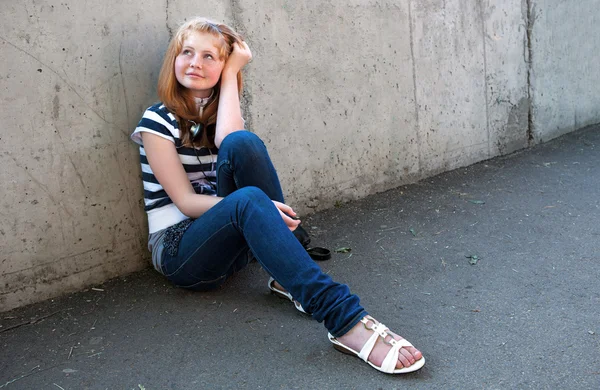 Portrait of a happy young girl sitting in street — Stock Photo, Image