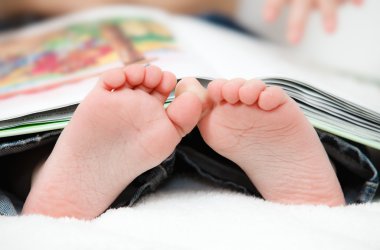 Foot closeup.An image of a toddler reading a book. clipart