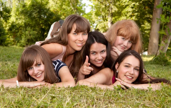 Grupp flickor tonåringar i parken på gräs — Stockfoto