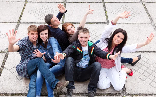 Grupp av manliga och kvinnliga studenter som sitter på gatan — Stockfoto