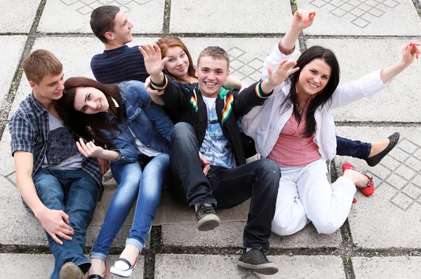 Grupp av manliga och kvinnliga studenter som sitter på gatan — Stockfoto
