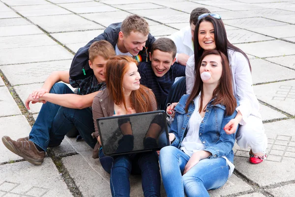 Gruppo di studenti di sesso maschile e femminile seduti con un computer portatile su stree — Foto Stock