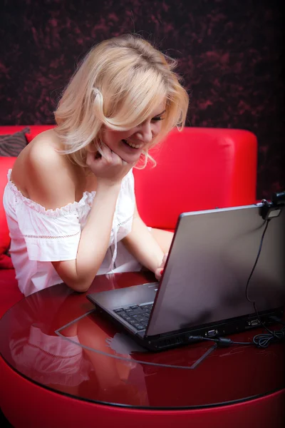 Улыбающаяся женщина с ноутбуком на диване в кафе — стоковое фото