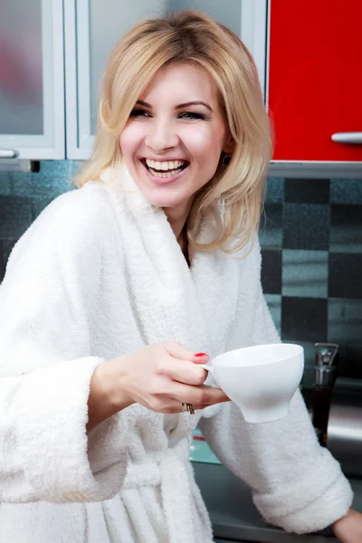 Mooie jonge Kaukasische vrouw in de keuken met kop thee — Stockfoto
