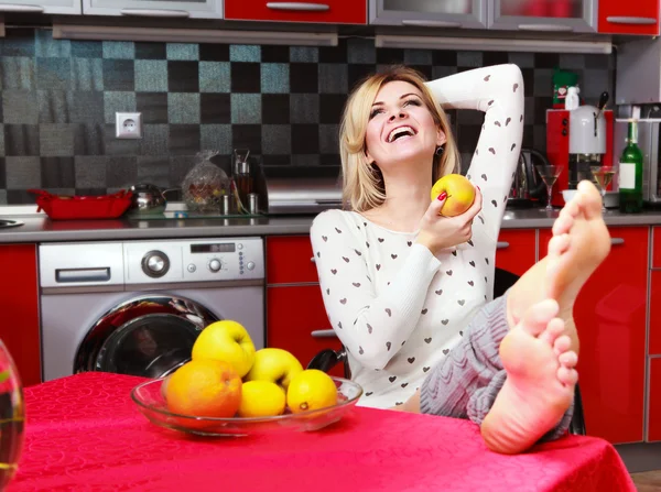 Ganska leende ung kvinna sitter i köket med frukt — Stockfoto