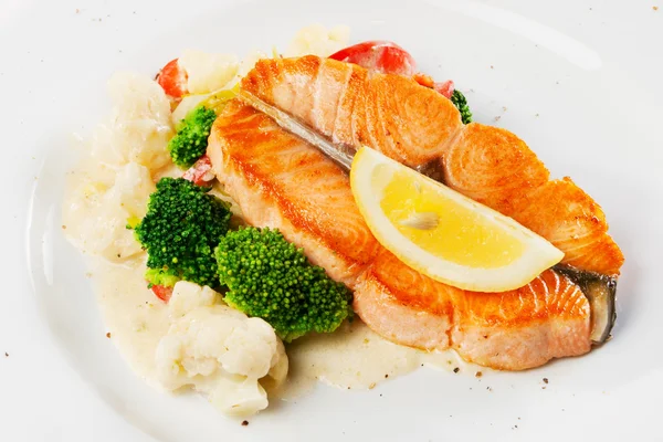 鱼菜-烤三文鱼与花椰菜、 青花菜和柠檬 免版税图库照片