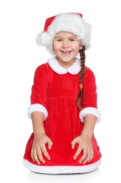 Joyeux petite fille dans le chapeau de Père Noël est assis sur un fond blanc — Photo