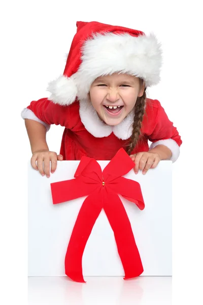 Happy little girl in Santa hat looks out of gift box — Stock Photo, Image