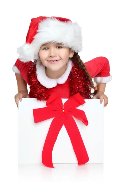 サンタの帽子の幸せな女の子はギフト用の箱の外に見える — ストック写真