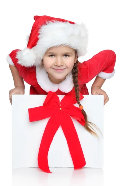 Happy little girl in Santa hat looks out of gift box — Stock Photo, Image