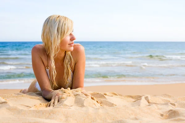 Mladá žena ležící na písku — Stock fotografie
