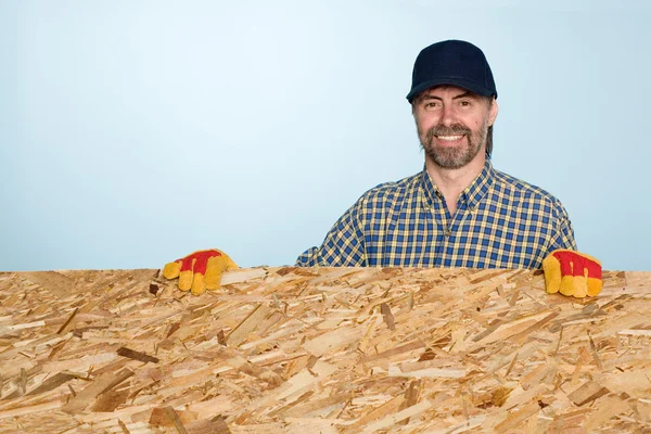 Smiling carpenter holds plywood — Stock Photo, Image