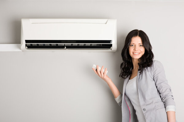 Girl holding a remote control air conditioner
