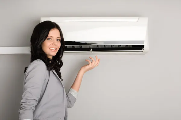 Girl showing the air conditioner — Stock Photo, Image