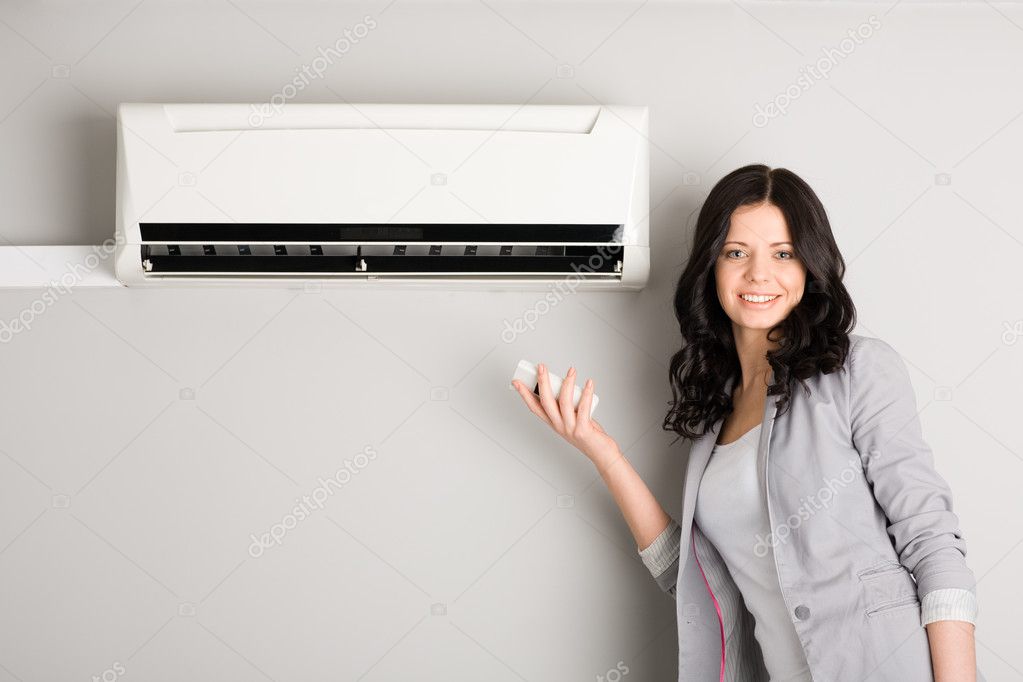 Girl holding a remote control air conditioner