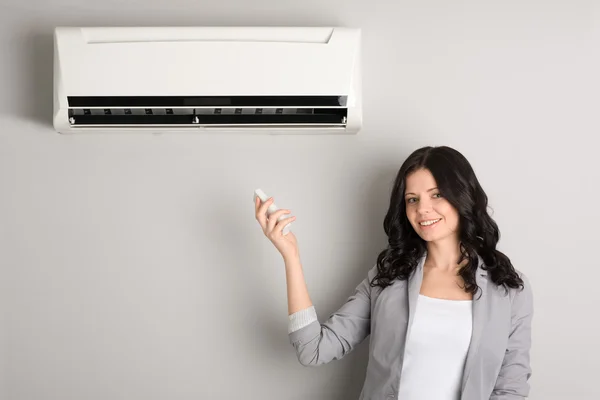 Meisje met een afstandsbediening airconditioner — Stockfoto