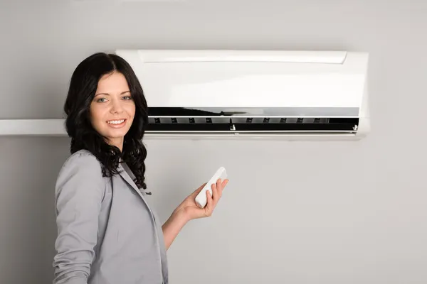 Girl with a remote control air conditioner — Stock Photo, Image