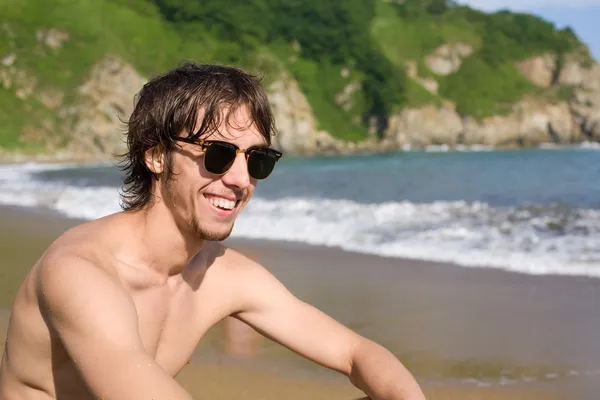 Young man sunbathes on beach — Stock fotografie