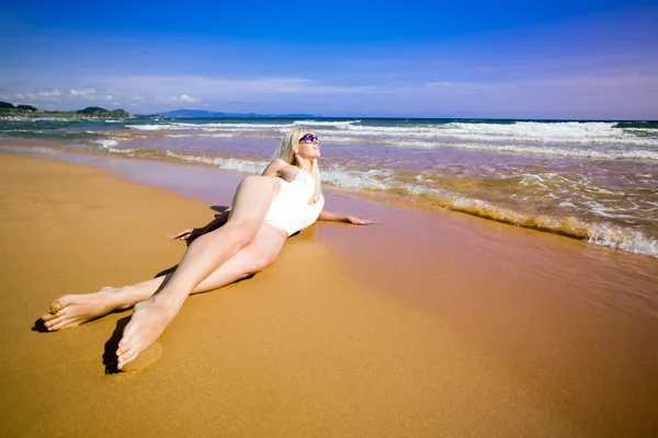 Młoda kobieta, leżąc na plaży — Zdjęcie stockowe