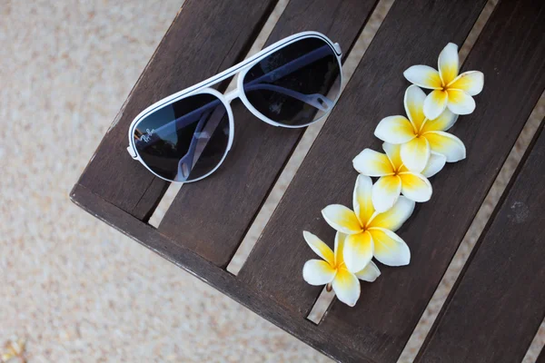Тропические цветы и солнечные очки на скамейке — стоковое фото