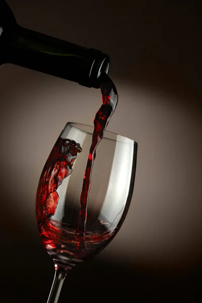 Red wine pouring in glass over dark background — Stock Photo, Image