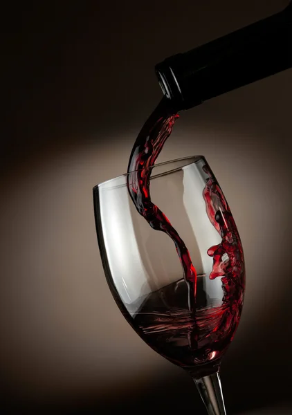 Rødvin hældes i glas over mørk baggrund - Stock-foto