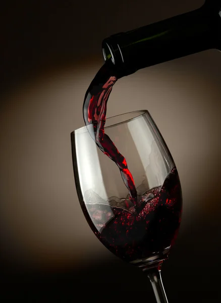 在玻璃中倾吐深色背景的红酒 — 图库照片