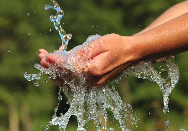 Женские руки с брызгами воды — стоковое фото