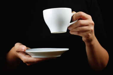 Cup of coffee in the women's hand on black background clipart