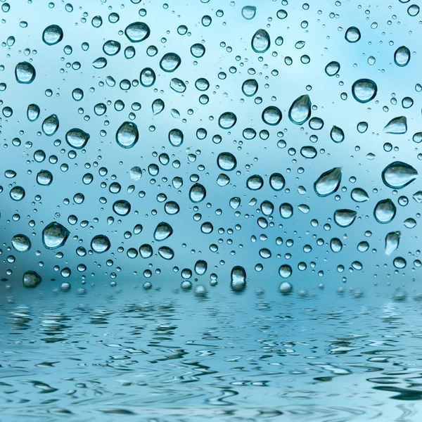Blauwe druppels weerspiegeld in het water — Stockfoto