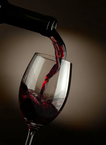 在玻璃中倾吐深色背景的红酒 — 图库照片