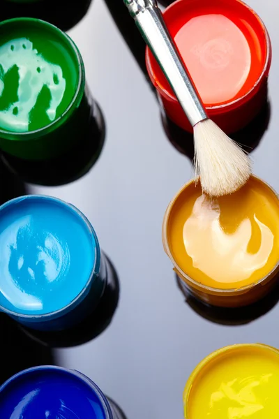 Paint buckets with paintbrush over dark background — Stock Photo, Image