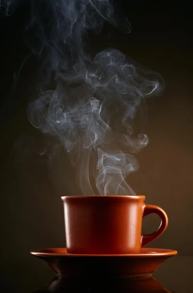Cup of coffee with smoke over dark background