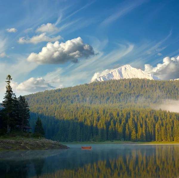 Paysage avec ciel bleu, montagnes, lac et bateau solitaire — Photo