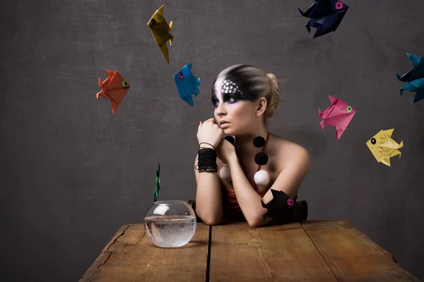 The girl, small fish, table, an aquarium,origami — Stock Photo, Image