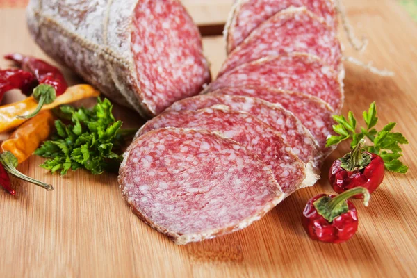 stock image Sliced salami with chili peppers and herbs