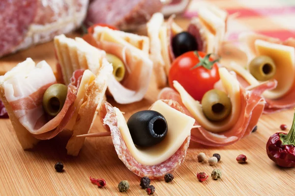 Canapé met gepekelde olijven, salami en prosciutto — Stockfoto